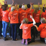 Group of volunteers with their backs to the camera showing off the back of the t-shirt