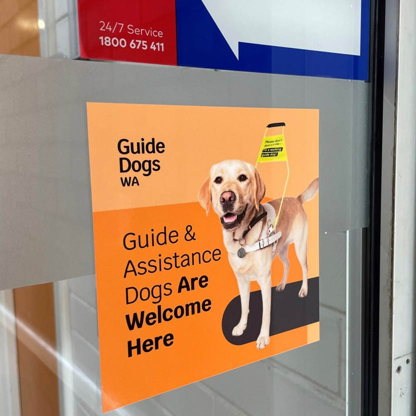 Sticker on the door an orange sticker on a glass workplace door with text guide and assistance dogs are welcome here