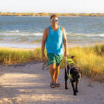 Jeremy and Guide Dog Nina walking along beach pathway.
