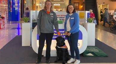 Guide Dogs WA staff member and Cancer Council WA staff member standing in shopping centre with Ambassador Dog.